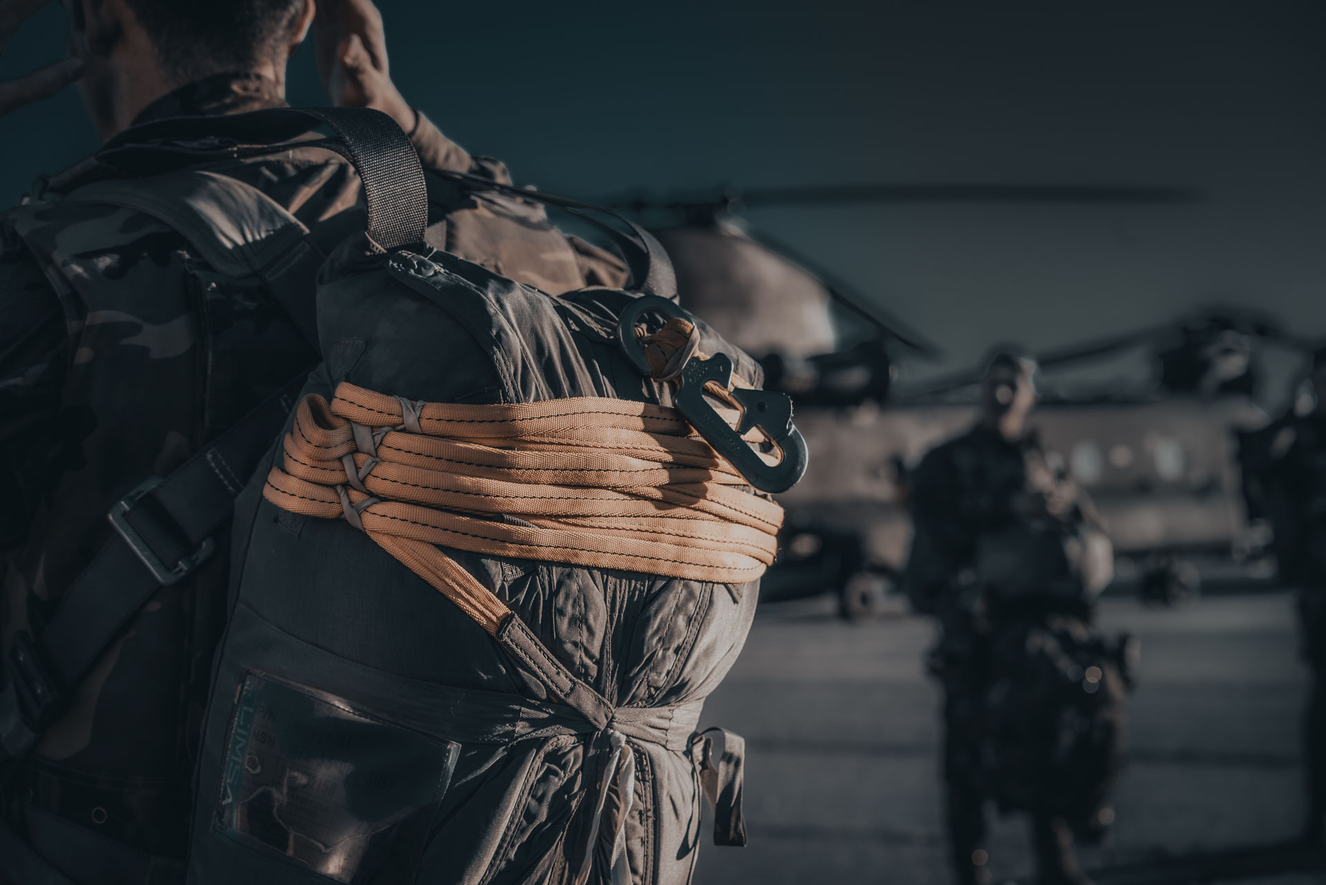 Military personnel with gear on airfield near helicopter